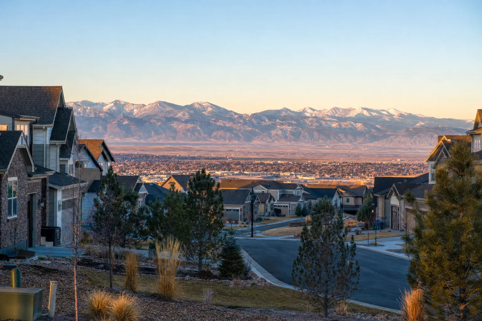 A Denver-area suburban neighborhood at sunrise with the Rocky Mountain front range on the horizon